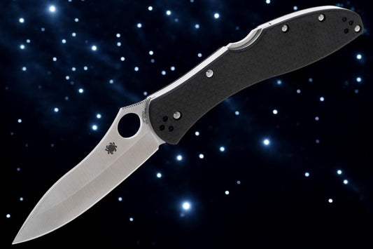 A Spyderco Centofante 3 gentleman's folder knife with a carbon fiber handle and a satin finish on the blade, set against a starry background.